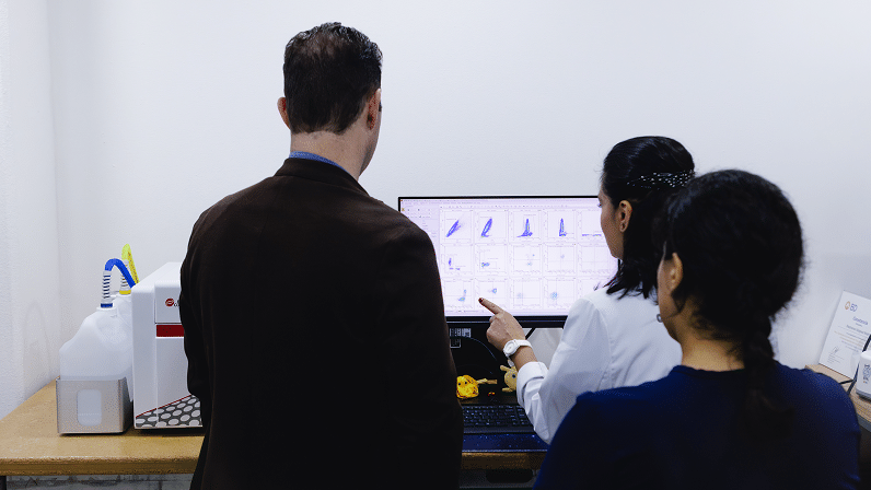 Three Immunocine team members reviewing immune-cell data on a computer screen in the lab.